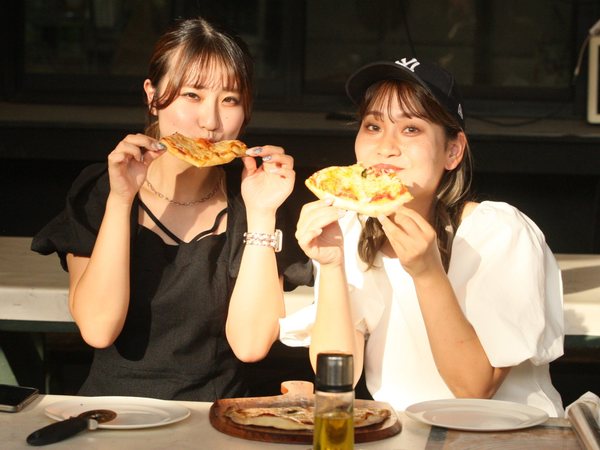 焼きたてのピザを手に並んで座る2人