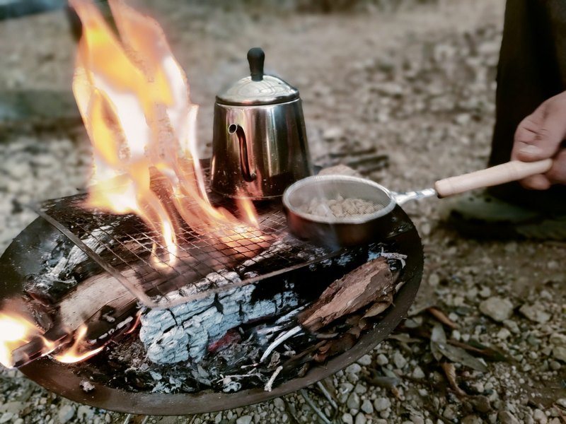 焚き火にかけたケトルと生豆のロースト